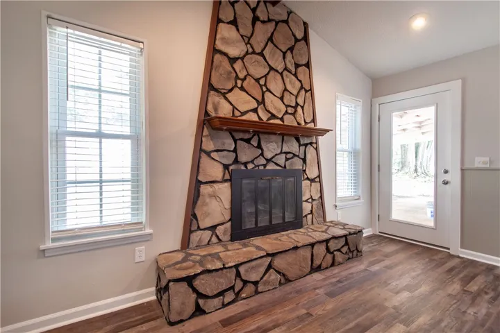 A striking stone fireplace hearth and surround anchors this inviting, wood-floored living space.