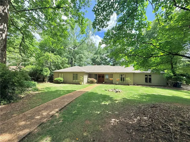 A charming ranch-style home nestled in a natural, tree-filled landscape.