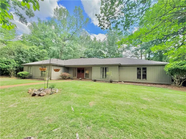 A peaceful suburban home with a manicured front yard, surrounded by lush, mature trees.