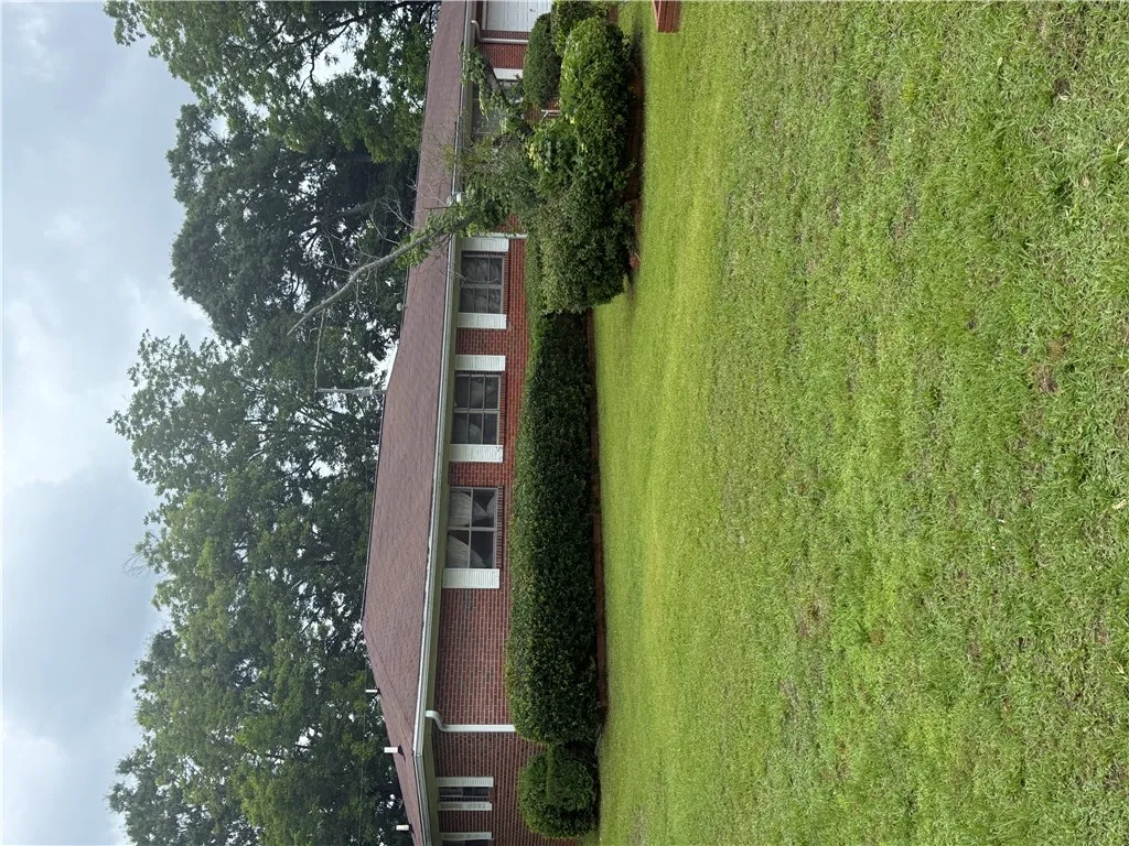 A well-maintained brick exterior residence with a neat, mature lawn and verdant landscaping.