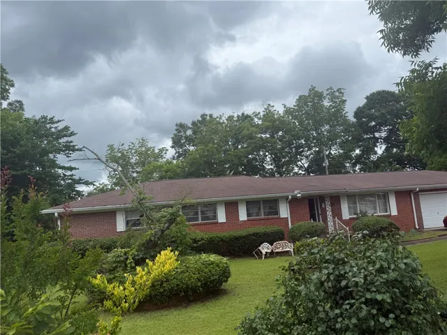 Brick facade home featuring a lush front lawn and mature trees, offering timeless appeal.
