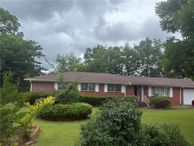 Mature trees and neat landscaping frame this classic brick facade with a charming front entrance.