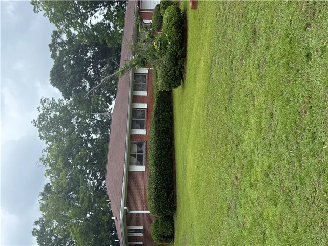 A well-maintained brick exterior residence with a neat, mature lawn and verdant landscaping.