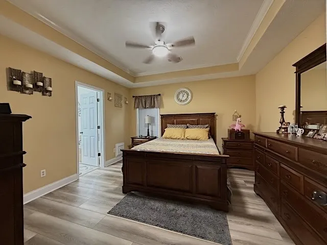 Recessed lighting highlights the elegant tray ceiling and durable laminate flooring in this bedroom retreat.