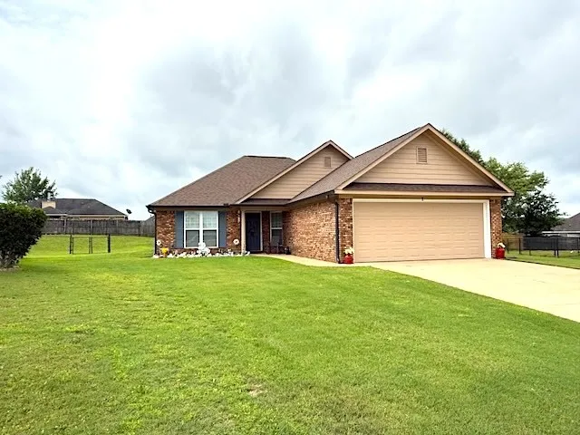 Brick and siding complement this charming single-story residence with an attached garage.