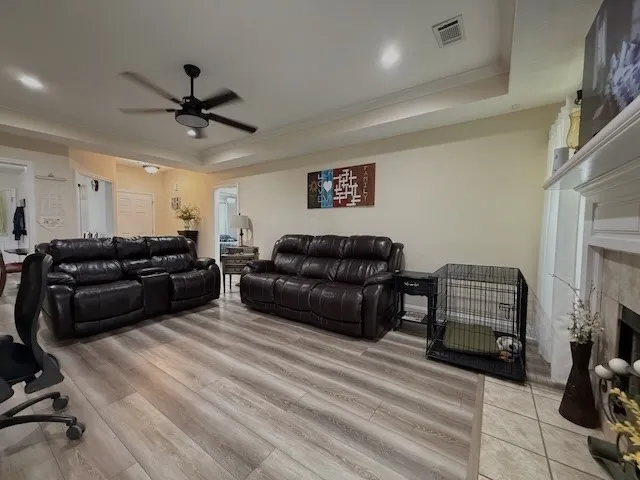 A comfortable living space boasts durable laminate flooring, a refined fireplace, and a tray ceiling.