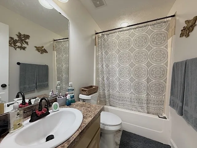 A classic tub and shower combination with patterned curtain and a spacious vanity.