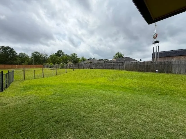 A spacious, verdant yard enclosed by fencing offers ample room for recreation.