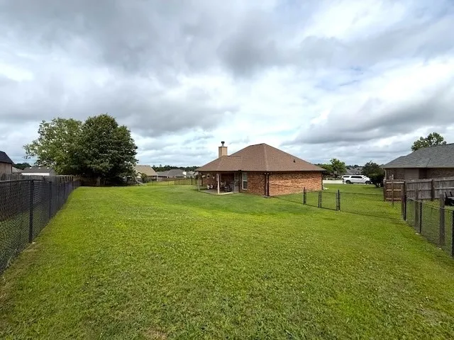 A generously sized yard, securely enclosed with durable chain-link fencing.