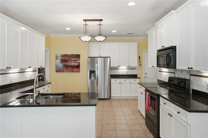 A well-appointed kitchen features dark granite countertops, crisp white cabinetry, and practical tile flooring.