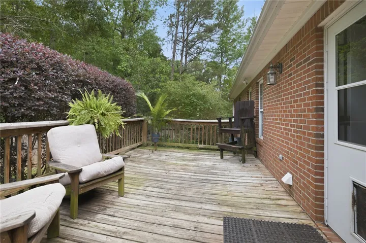 A spacious wooden deck provides ample outdoor living space, framed by lush foliage.