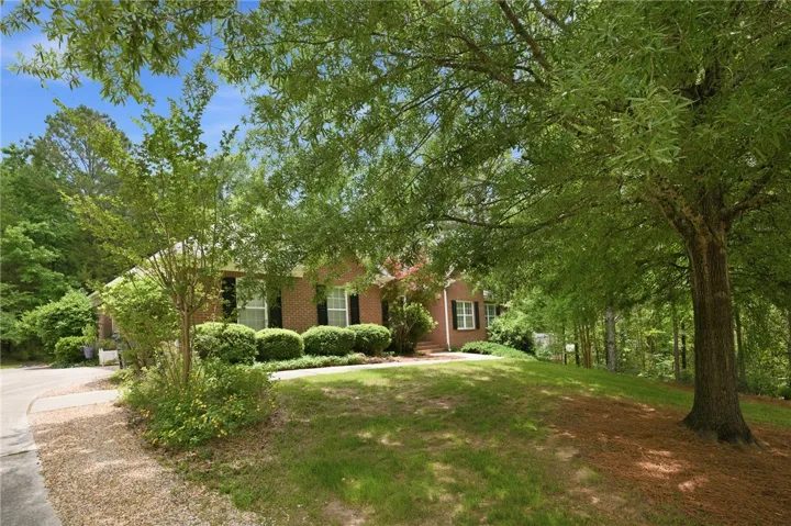Mature trees canopy the entry to this classic brick residence, set on a gentle slope.