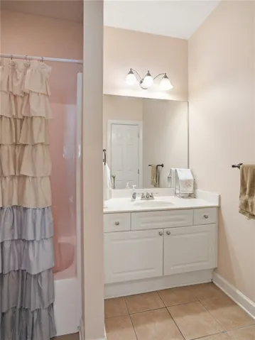Functional bathroom with a white vanity and tiled flooring.