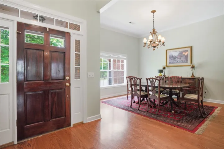 A spacious dining area with hardwood floors, a large window, and an elegant chandelier awaits.