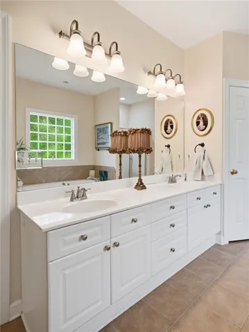 A well-appointed primary bath features a spacious double vanity, a large mirror, and tiled flooring.