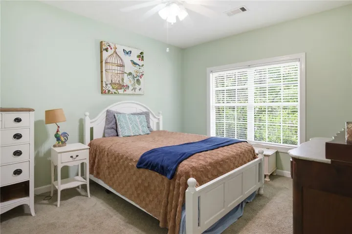 A comforting bedroom with soft carpeting and ample natural light from a well-lit window.