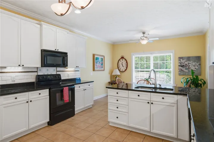 A well-lit kitchen with sleek black appliances and ample counter space for culinary endeavors.