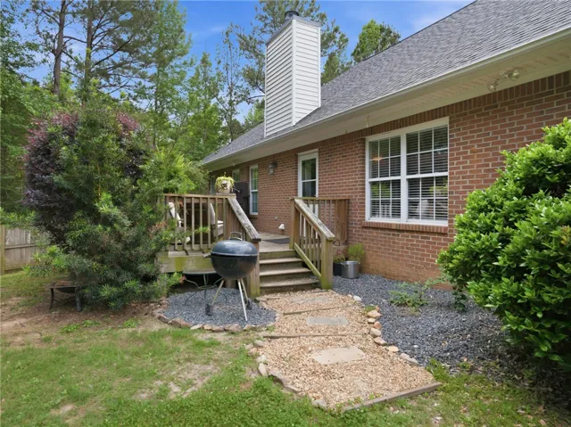 A private backyard oasis features a brick exterior, a wooden deck, and a charming gravel path.