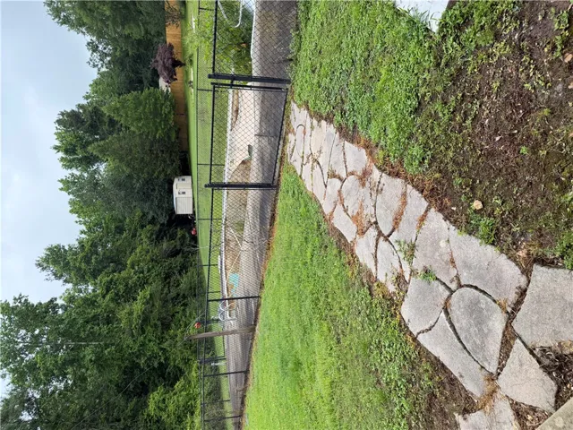 A stone pathway guides through the green yard, leading to a fenced pool area.