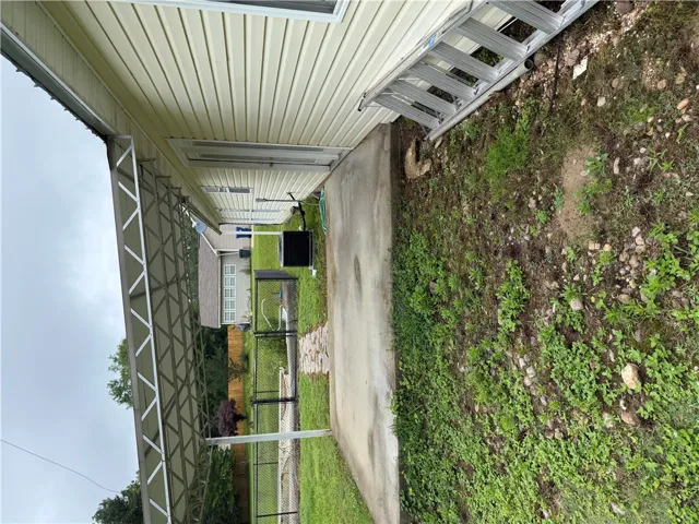 A well-maintained side yard with a practical covered carport and mature landscaping.