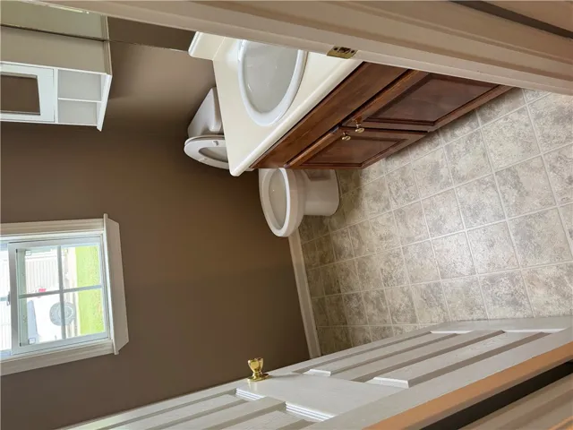 Functional primary bathroom features a warm neutral palette with a window offering natural light.