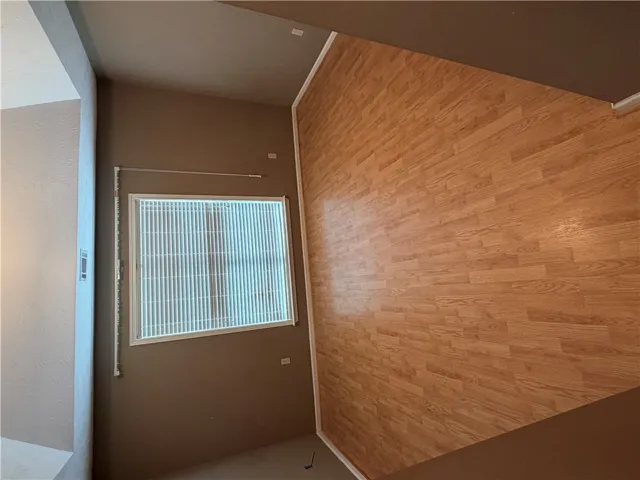 A well-lit interior space offers a view through a window, complemented by warm wood flooring.