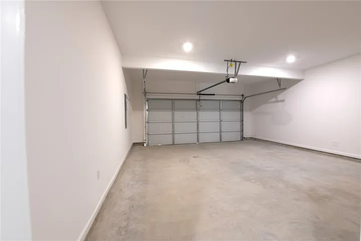 An attached garage provides durable concrete flooring and recessed lighting.