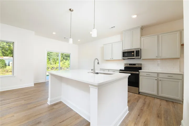 An airy culinary space pairs sleek stone countertops with durable wood-look flooring.
