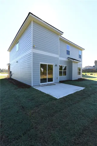 A concrete patio extends from the back of this two-story home with siding.