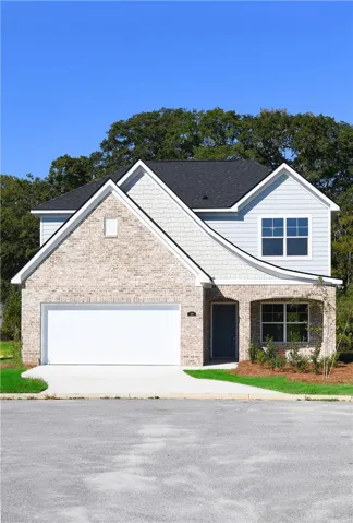 Multi-textured siding and classic brickwork define this newly built two-story facade with an attached garage.