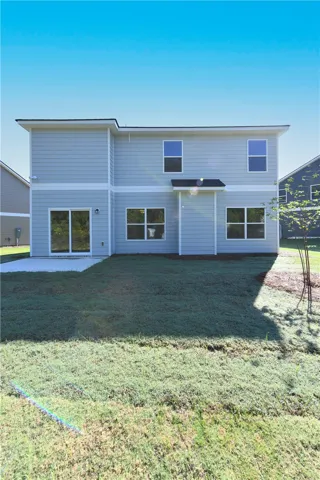 A spacious grassy lawn extends from the rear concrete patio of this modern home.