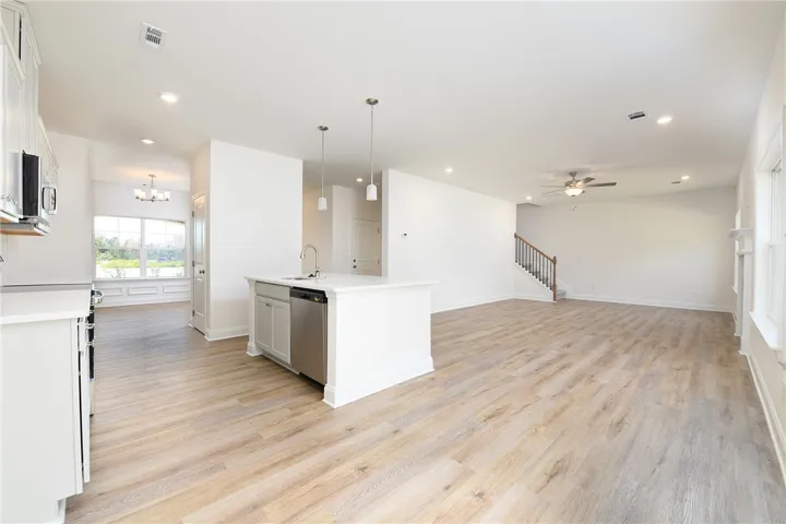 An open floorplan seamlessly connects the kitchen to a generous living area with light wood flooring.