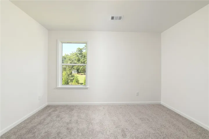 Plush carpeting and a picture window framing green views define this versatile bedroom.