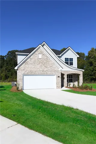 A pristine brick exterior defines this newly constructed traditional home under blue skies.
