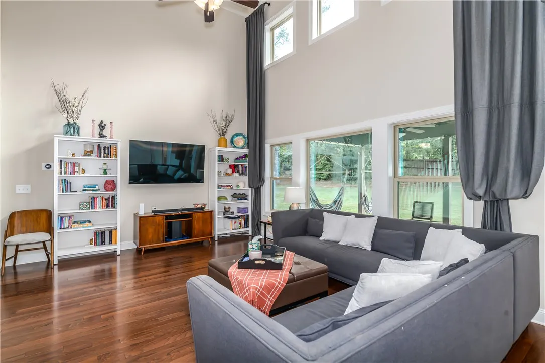 A spacious living room features soaring ceilings, rich hardwood flooring, and ample natural light.