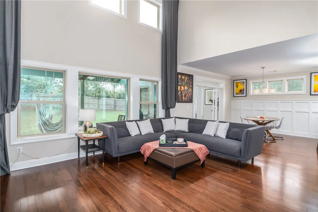 Natural light floods this living space, featuring high ceilings and rich hardwood flooring, perfect for gatherings.