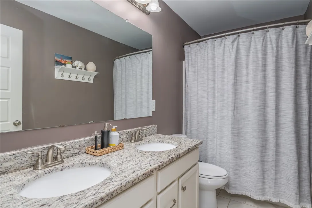 Double vanity with stone counters provides ample space in this well-appointed bathroom.