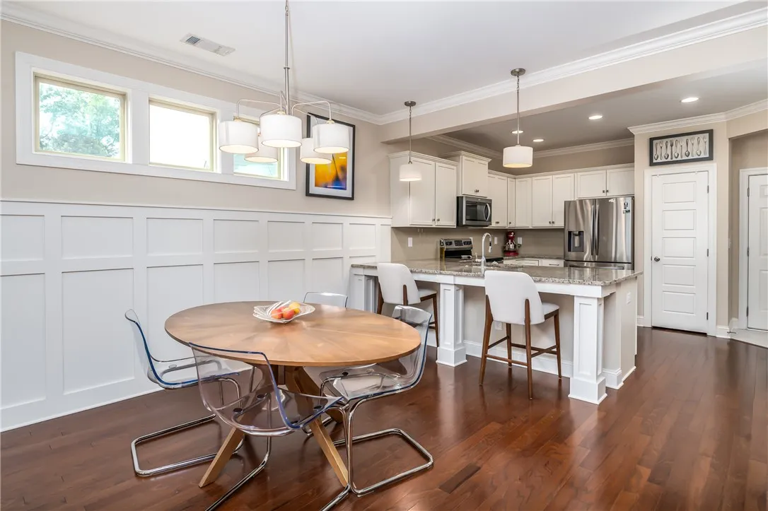 A vibrant kitchen with ample space for dining features rich hardwood flooring and sleek stainless steel appliances.