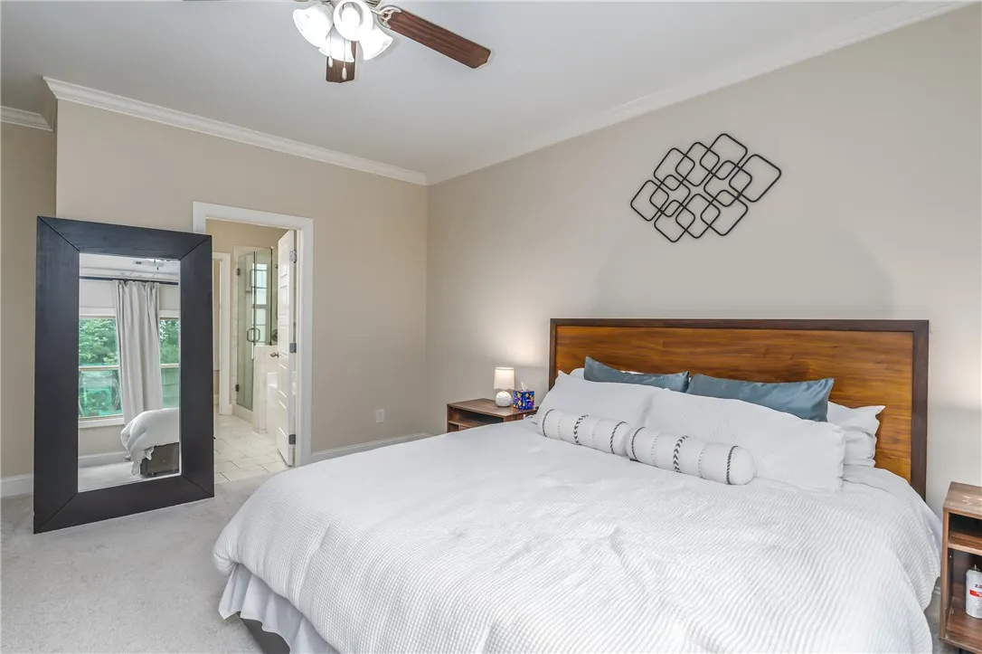 A tranquil primary bedroom with soft carpeting and a spacious, well-lit adjoining bath beyond the open door.