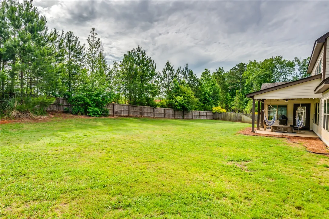 A deep backyard offers privacy and ample green space for outdoor activities, complementing the covered patio.
