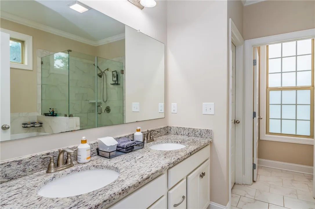 Granite counters and double vanities elevate this light-filled bath, complete with a glass-enclosed shower.