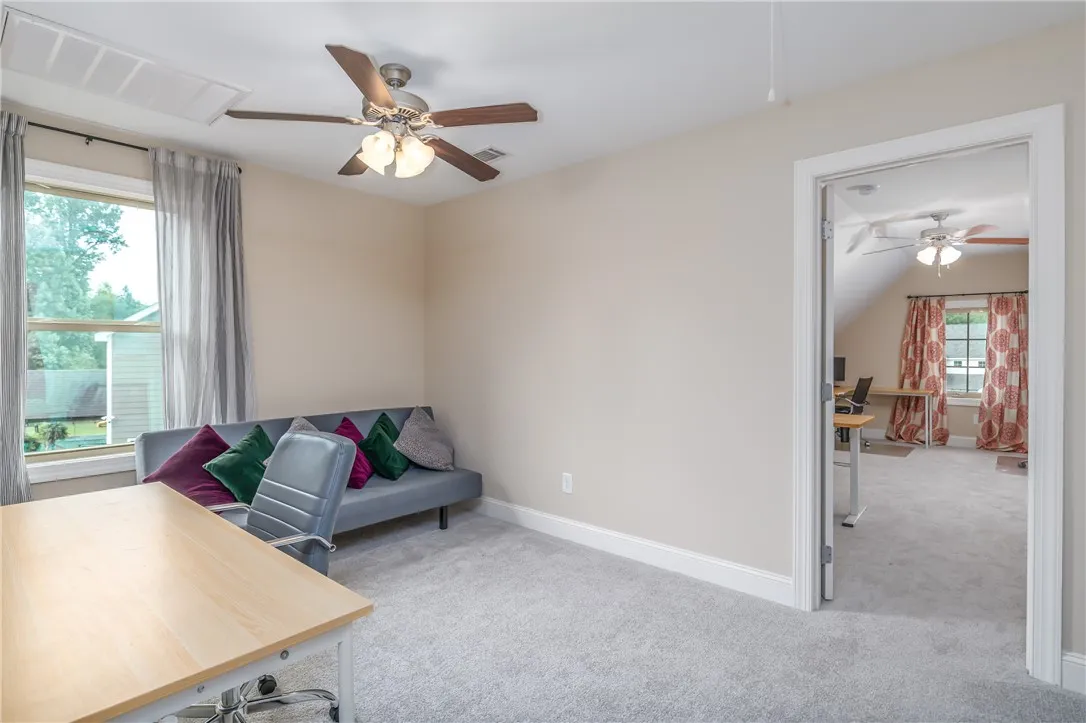 A versatile office space provides comfort and functionality with carpet flooring and ample natural light.