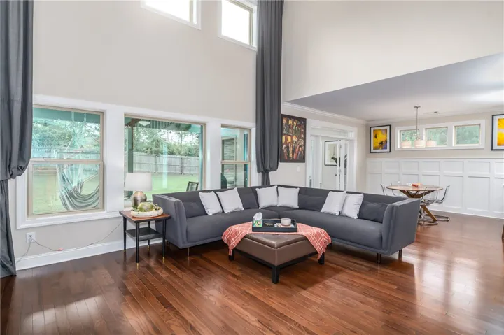 Natural light floods this living space, featuring high ceilings and rich hardwood flooring, perfect for gatherings.