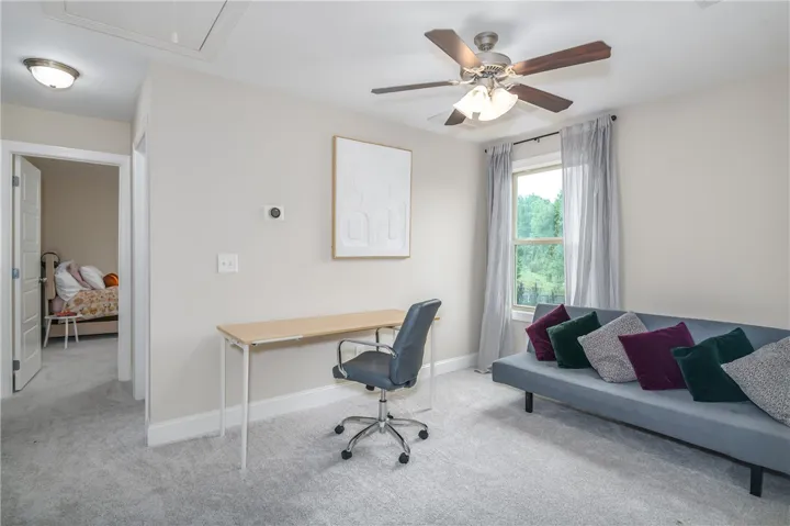 A versatile secondary room offers soft carpet flooring and a ceiling fan, ideal for a home office or extra living space.