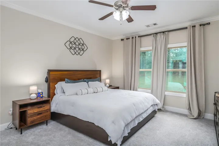 Relax in this well-appointed bedroom, featuring soft carpeting and a peaceful view of the outdoors.