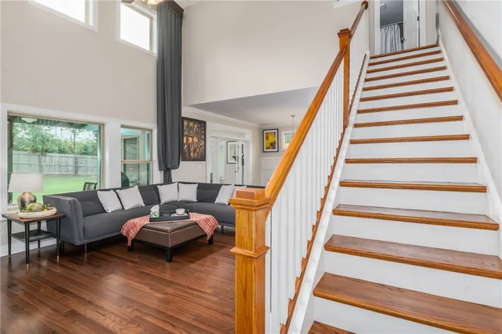 Hardwood flooring extends throughout the inviting living area, complemented by a striking staircase.