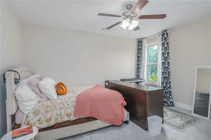 A well-lit bedroom provides comfortable living with soft carpeting and a bright window.