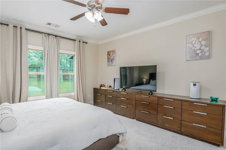 A naturally illuminated bedroom offers comfort with soft carpeting and crown molding accents.