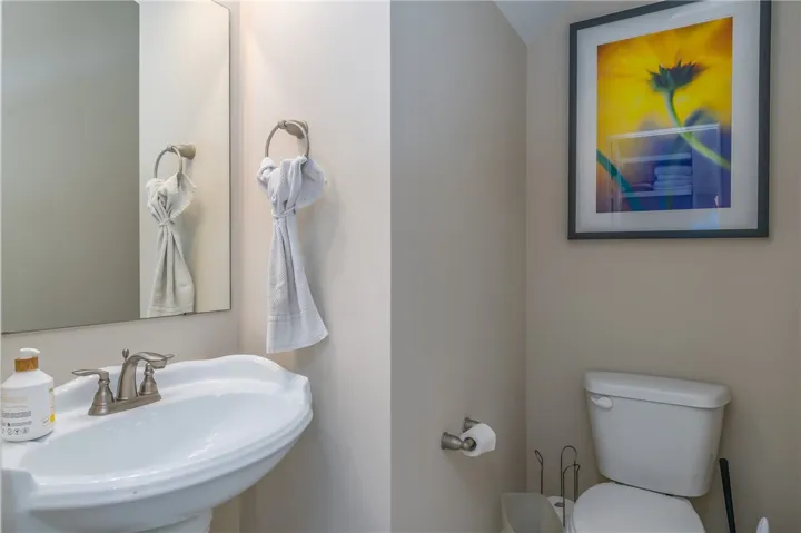 A compact and functional bathroom space, featuring a pedestal sink and bright, warm lighting.
