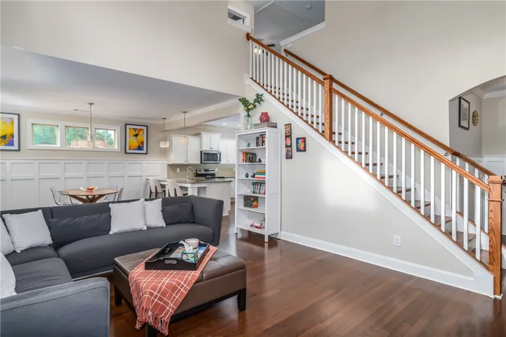 An open-concept living space with lustrous hardwood floors flows into a kitchen with modern appliances and a charming dining area.